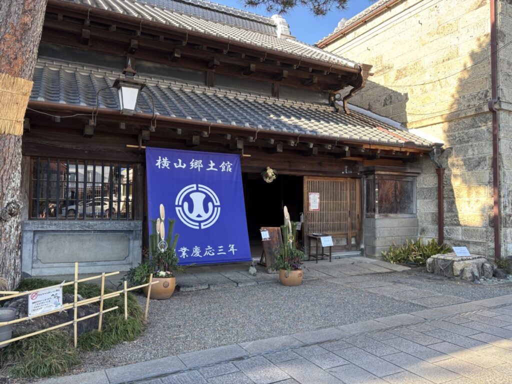 横山郷土館の蔵造りの外観と「創業慶応三年」の幟